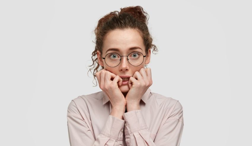 A woman with glasses covering her face with her hands.