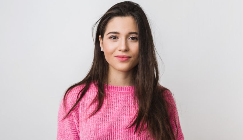 A young woman in a pink sweater posing for a photo.