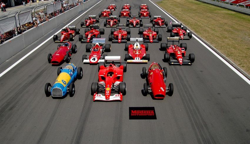 A group of red racing cars lined up on a race track.