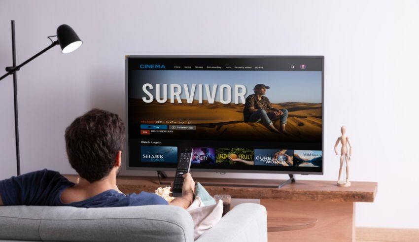 A man is sitting in front of a tv watching survivor.