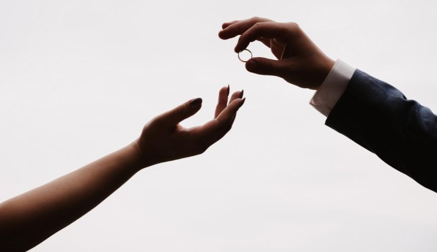 Two hands reaching for a wedding ring.