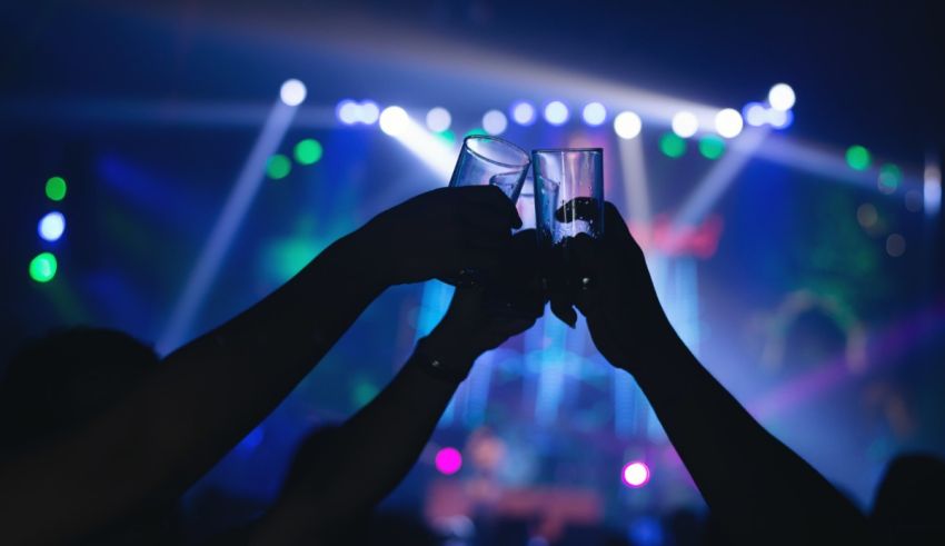 Two people toasting in front of a stage at a concert.