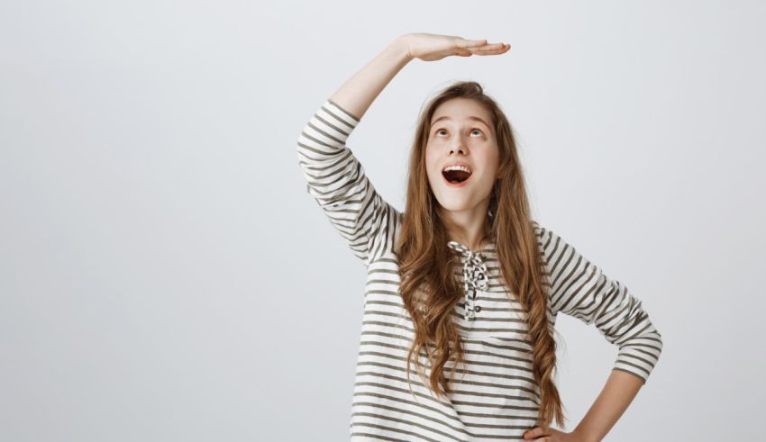 A young girl in a striped shirt is holding her hand up in the air.