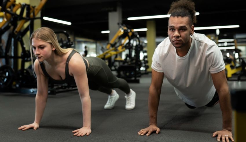 Two people doing push ups in a gym.