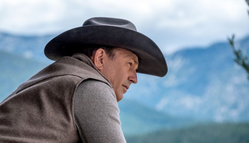 A man in a cowboy hat looking at the mountains.