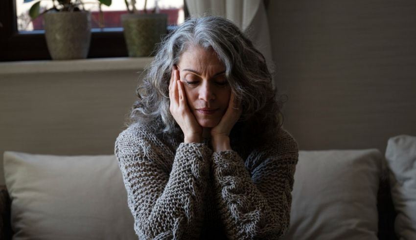 A woman sitting on a couch with her hands on her face.