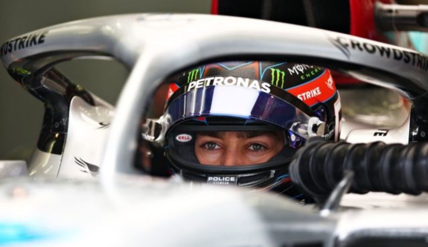 A mercedes driver sits in the cockpit of a racing car.