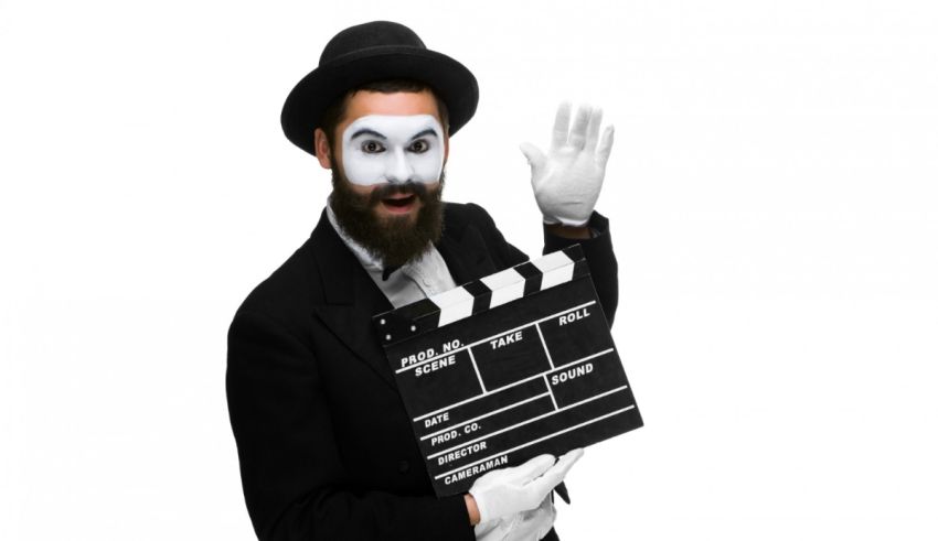 A man in a tuxedo holding a movie clapper.