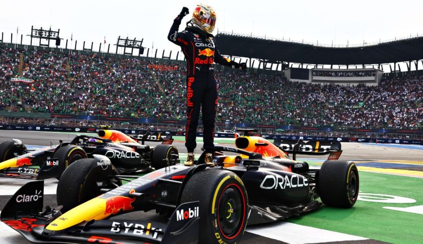 A red bull racing driver is standing on top of his car.