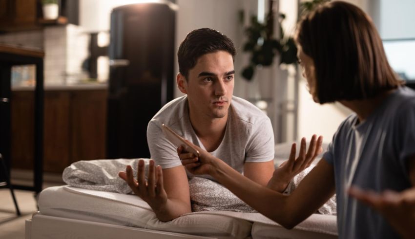 A man is talking to a woman on the bed.