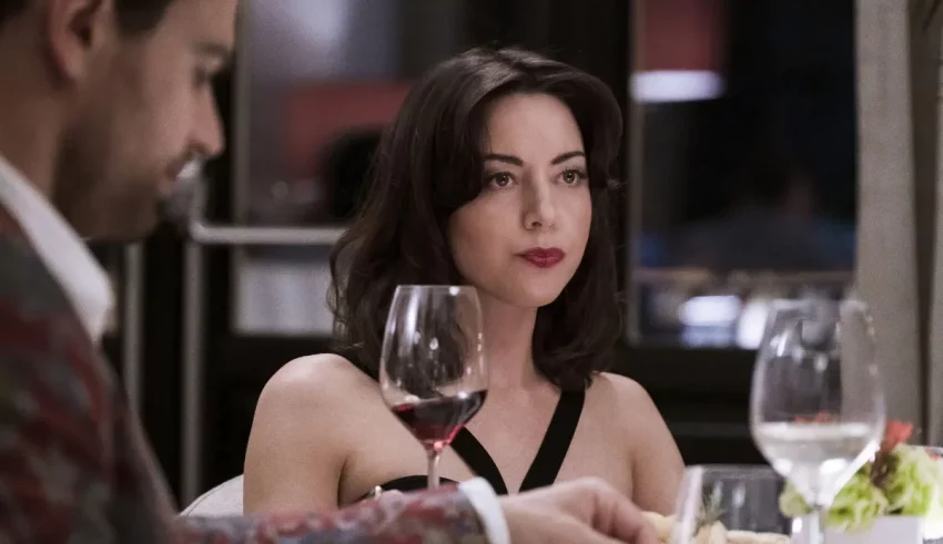 A woman sitting at a table with a glass of wine.