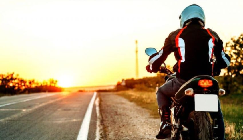 A person riding a motorcycle on a road at sunset.