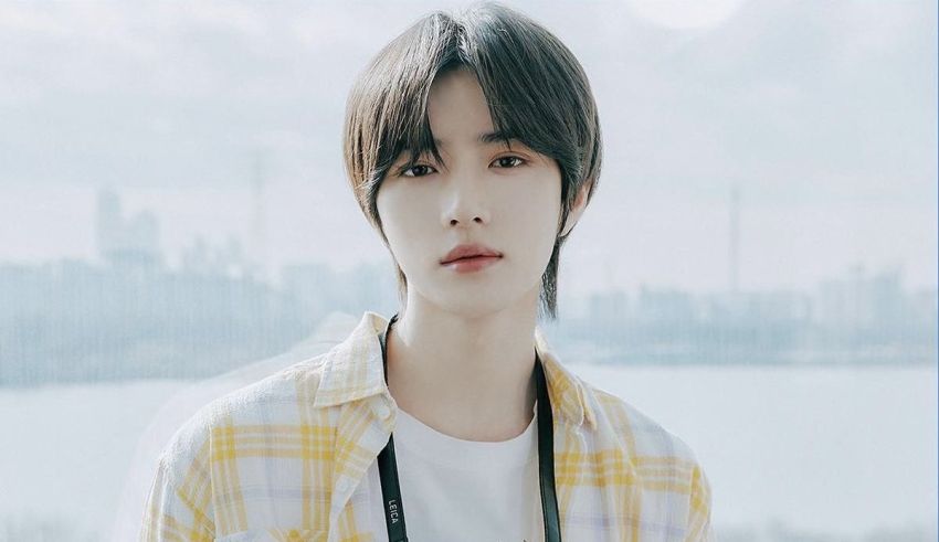 A young man in a yellow shirt is standing in front of a city.