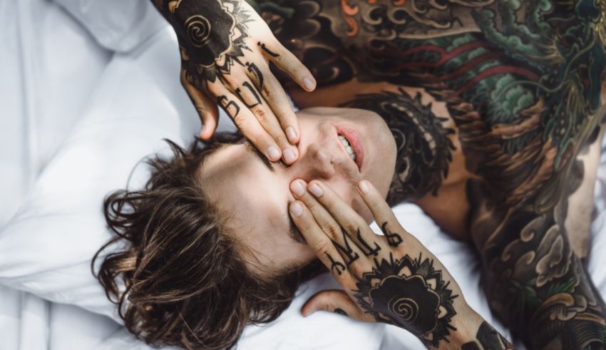 A man with tattoos laying on a bed.