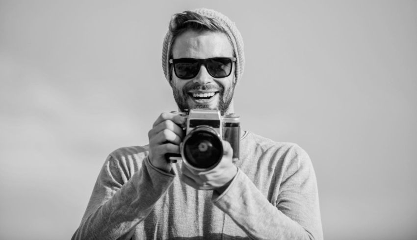 A black and white photo of a man holding a camera.