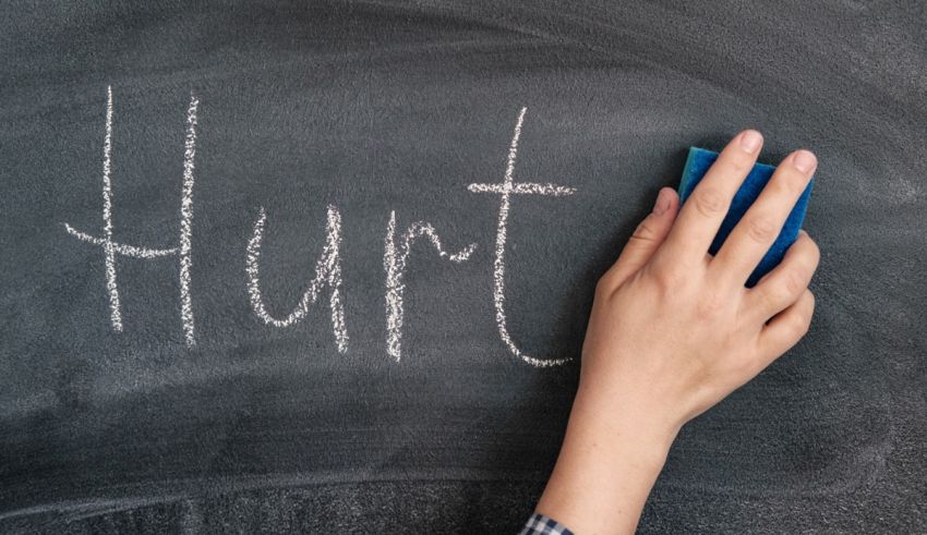 Hand writing the word hurt on a blackboard.