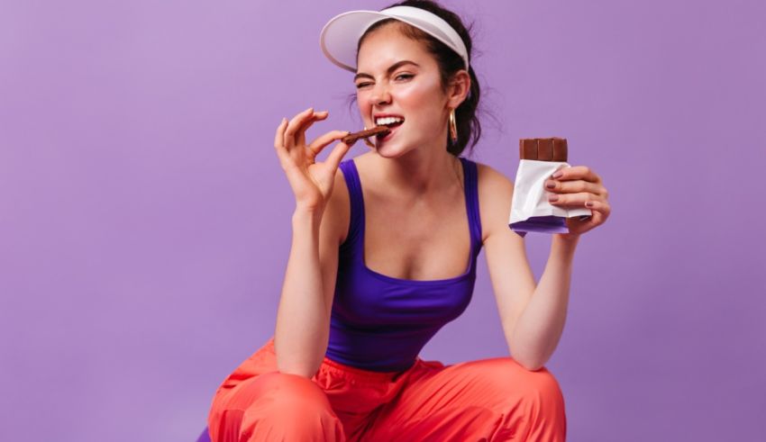 A woman is eating a chocolate bar on a purple background.