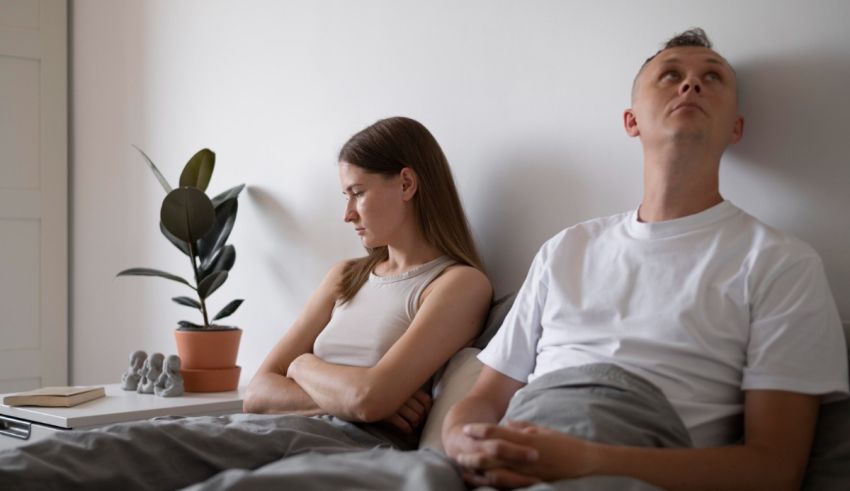 A man and woman are sitting on a bed and looking at each other.