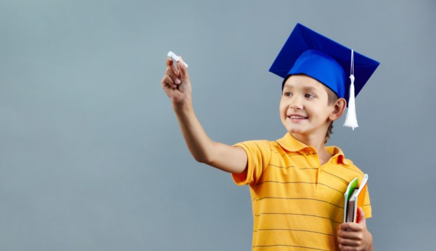 A young boy in a graduation cap pointing at something.