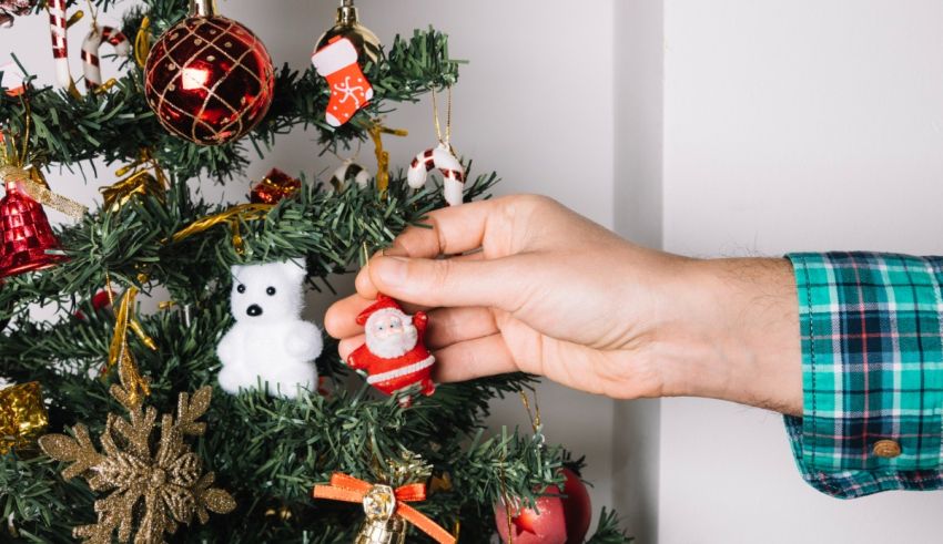 A man is putting ornaments on a christmas tree.