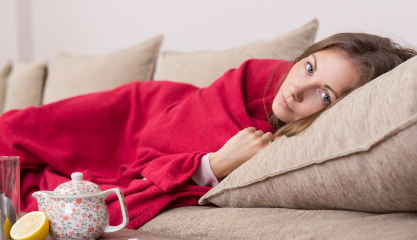 A woman wrapped in a red blanket on a couch.