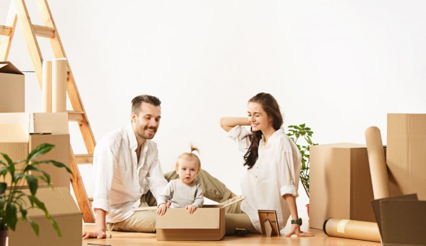 A family sits on the floor with boxes and a baby.