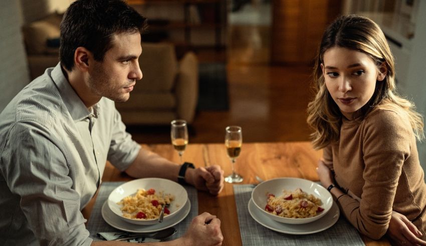 A man and woman sitting at a table eating pasta.