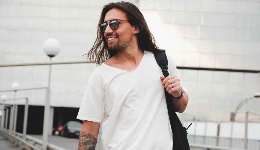 A man with long hair and tattoos walking down a street.