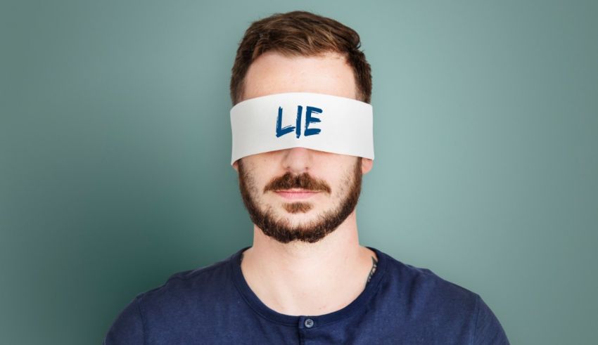 A man wearing a blindfold with the word lie on it.