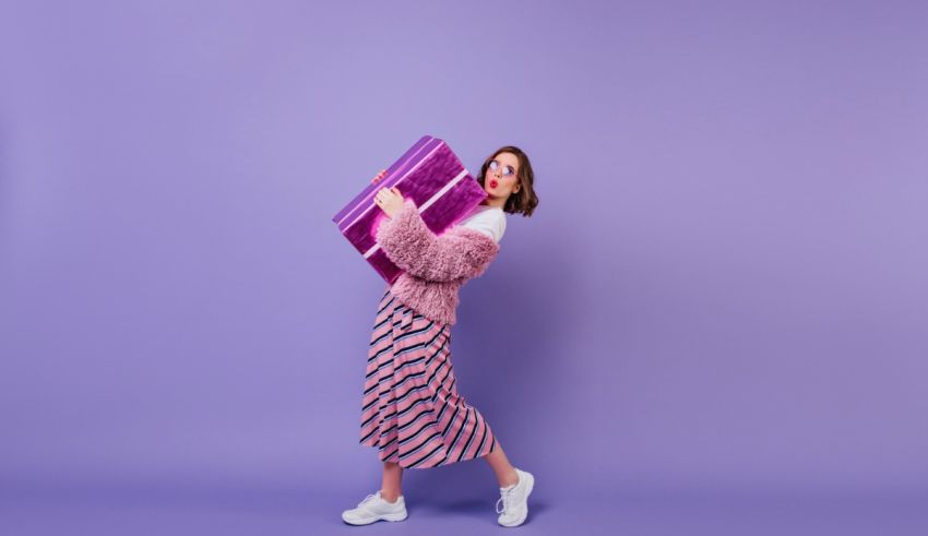 A woman holding a purple gift box on a purple background.