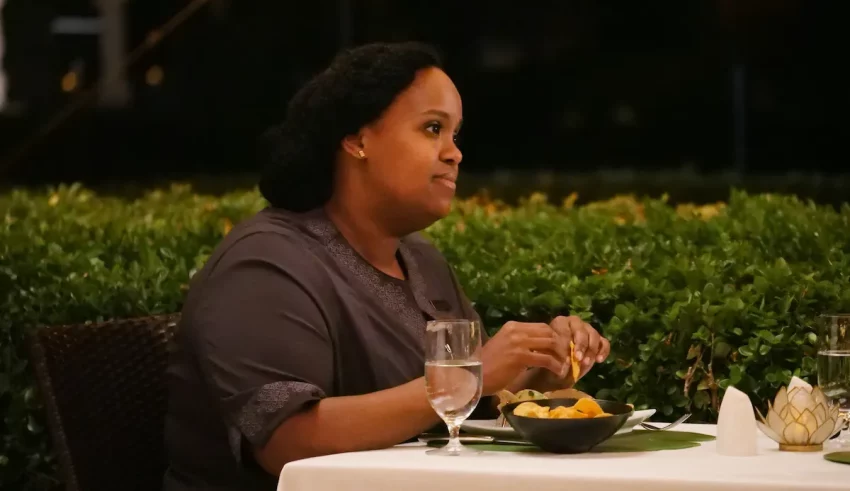 A woman sits at a table with food in front of her.