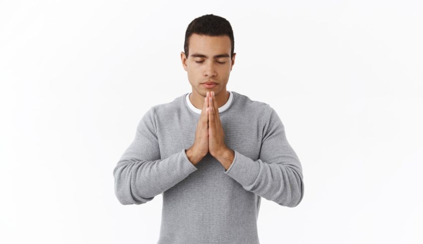 A man praying with his hands folded on a white background.