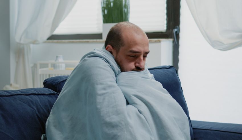 A man wrapped in a blanket sitting on a couch.