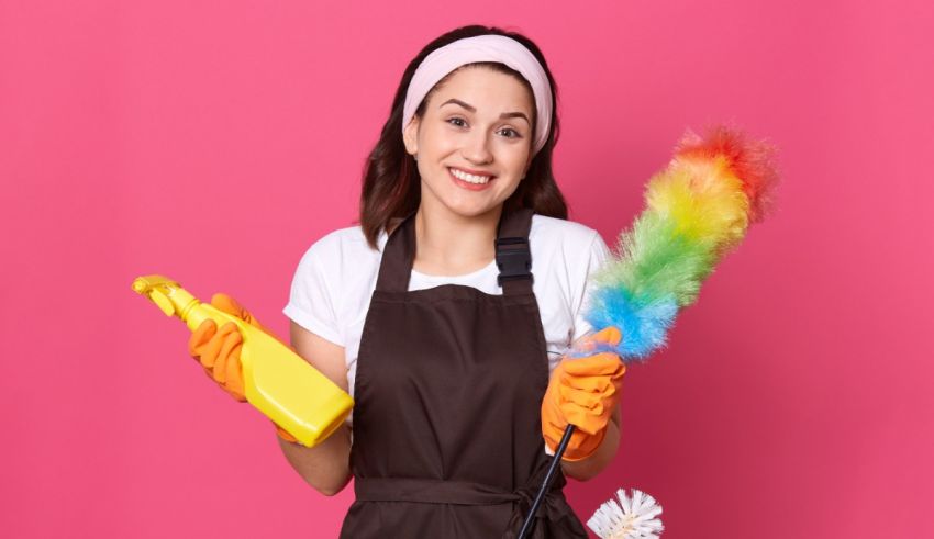 A woman in an apron holding a mop and cleaning supplies.