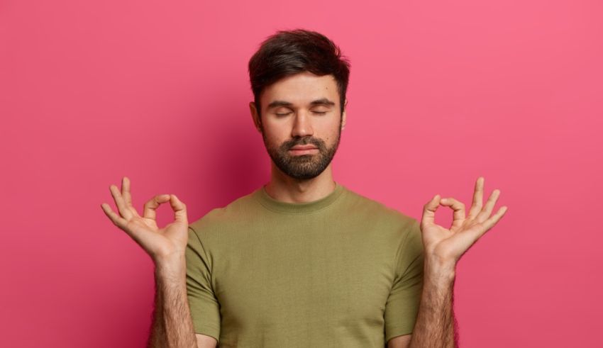 Young man meditating on pink background.