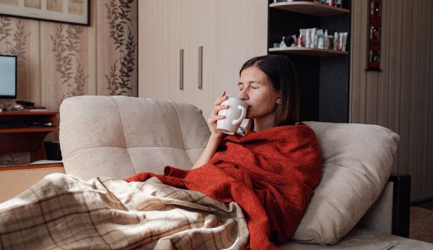 A woman is sitting on a couch with a cup of coffee.