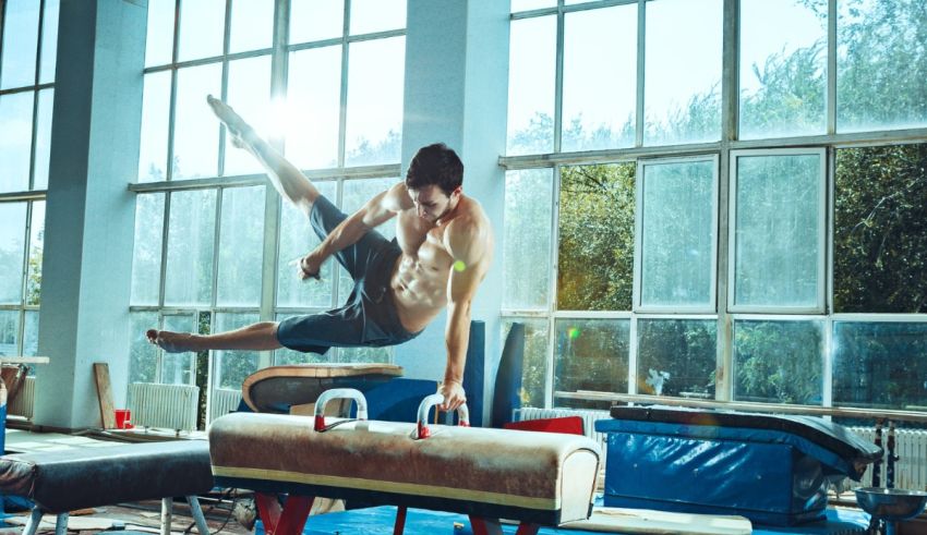 A man doing gymnastics on a beam in a gym.