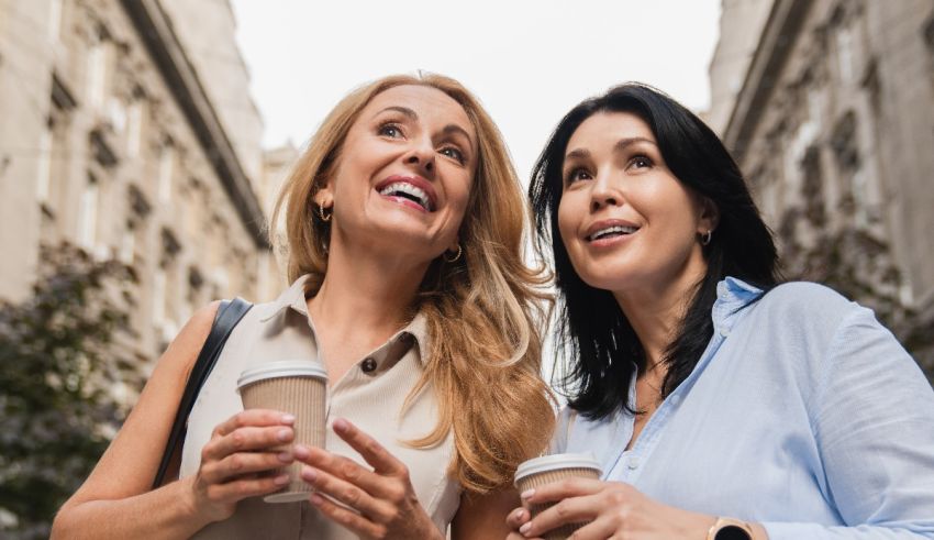 Two women looking at each other while holding coffee.