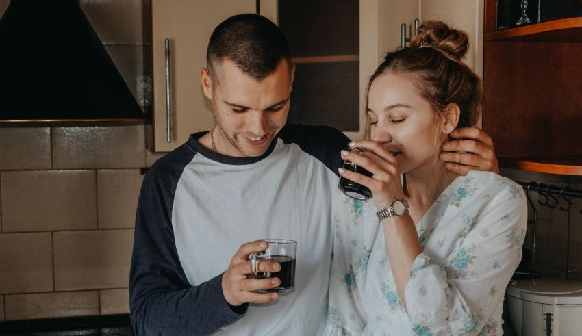 A man and woman drinking coffee in the kitchen.