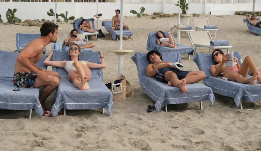 A group of people sitting on lounge chairs on the beach.