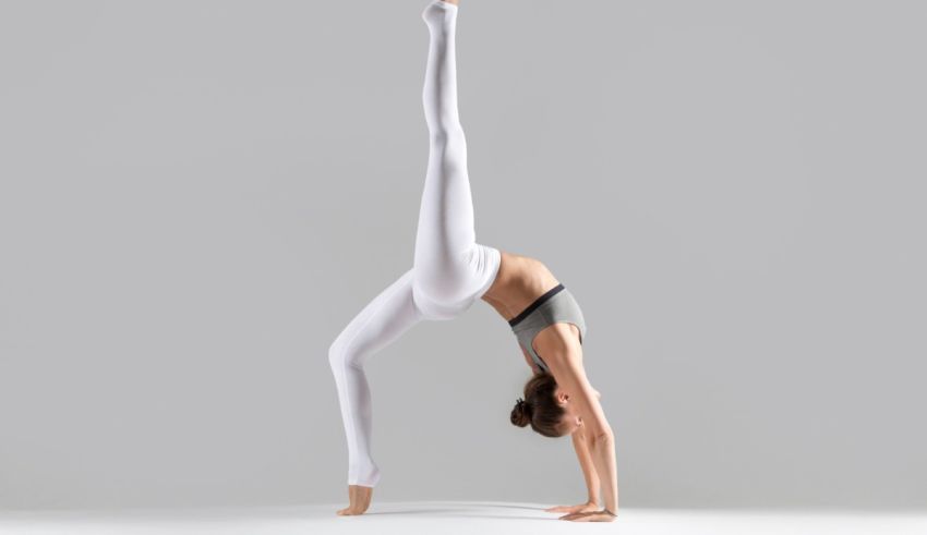 A woman doing a yoga pose on a gray background.