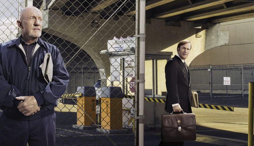 Two men standing next to a fence with briefcases.