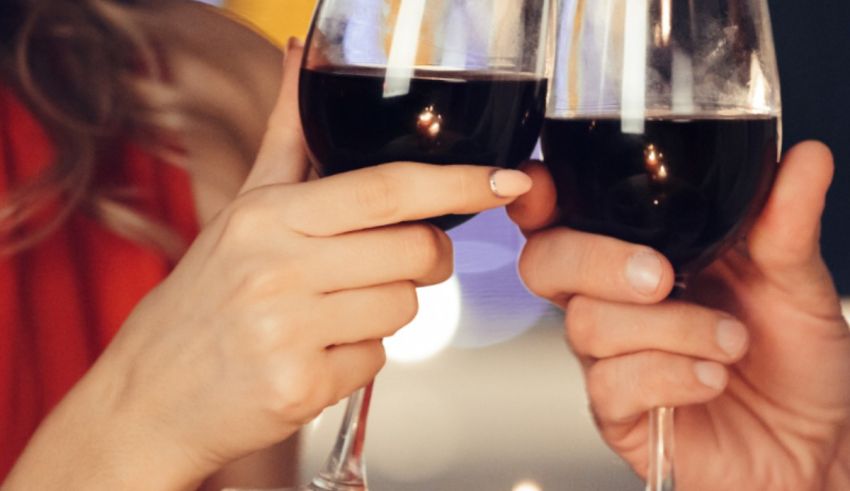 Two people toasting wine glasses in front of a candle.