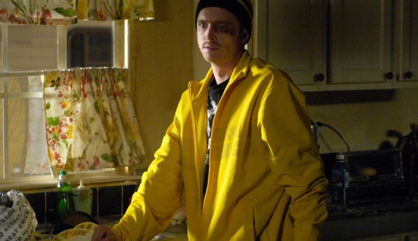 A man in a yellow jacket standing in a kitchen.