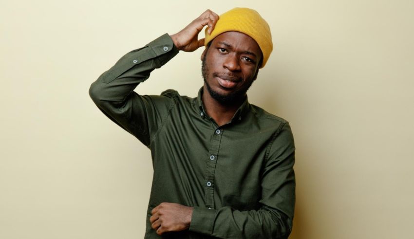 A black man wearing a yellow beanie posing on a yellow background.