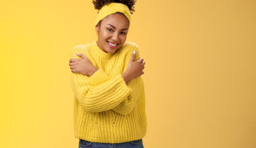 A young black woman in a yellow sweater posing on a yellow background.