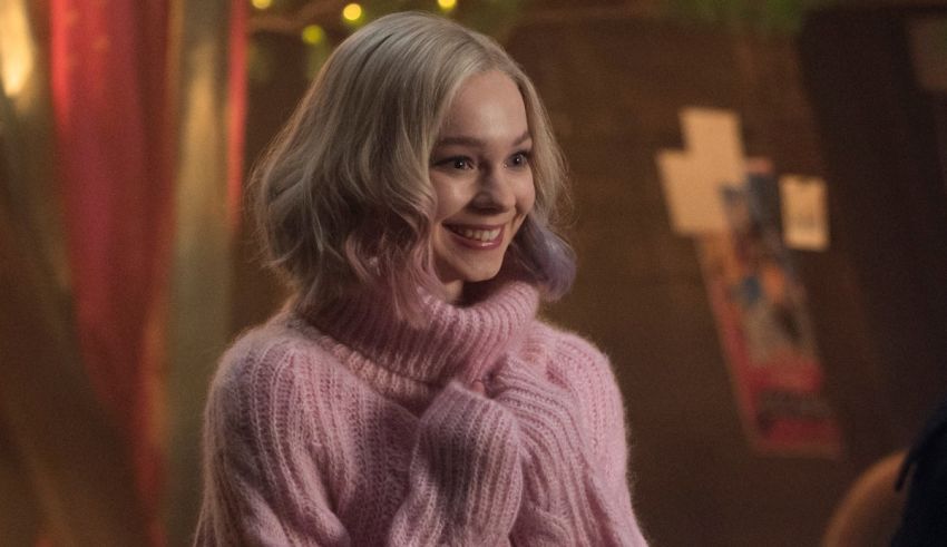 A woman in a pink sweater is smiling.