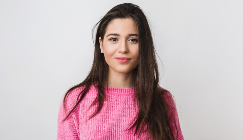A young woman in a pink sweater posing for a photo.