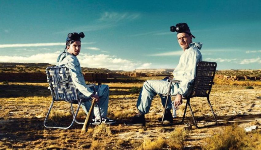 Two men sitting on chairs in a field.