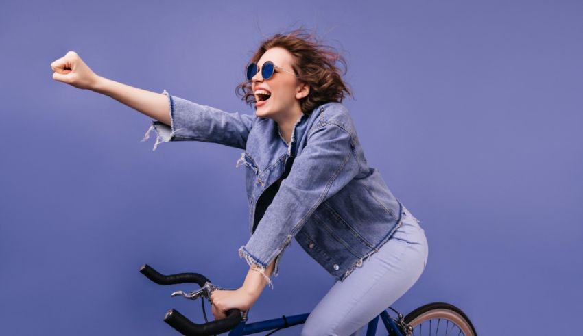 A woman is riding a bicycle with her arms up.